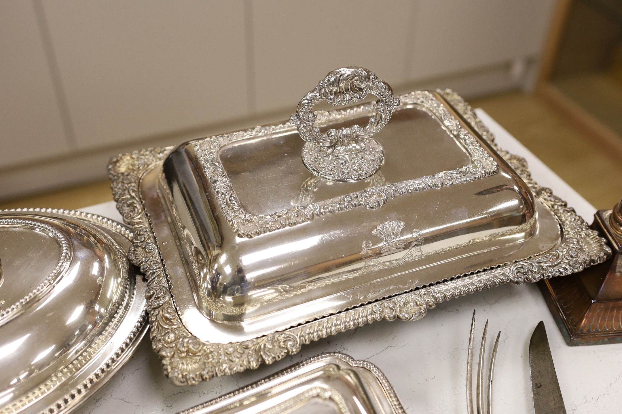 Three silver plated entrée dishes, a pair of candlesticks and a carving knife and fork, largest dish, 32 cms wide